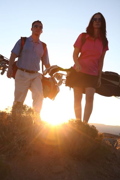 Man and woman walking with golf bags